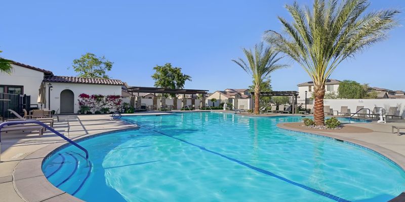 Community pool with lounge chairs and palm trees